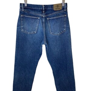 May include: A pair of blue denim jeans with a brown leather Wrangler label on the back pocket.