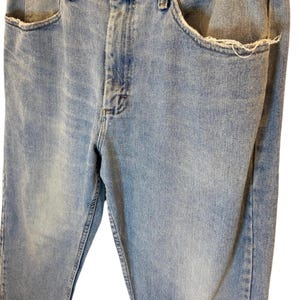 Peut inclure: Un jean en denim bleu clair avec une poche effiloch&eacute;e et une braguette &agrave; bouton.