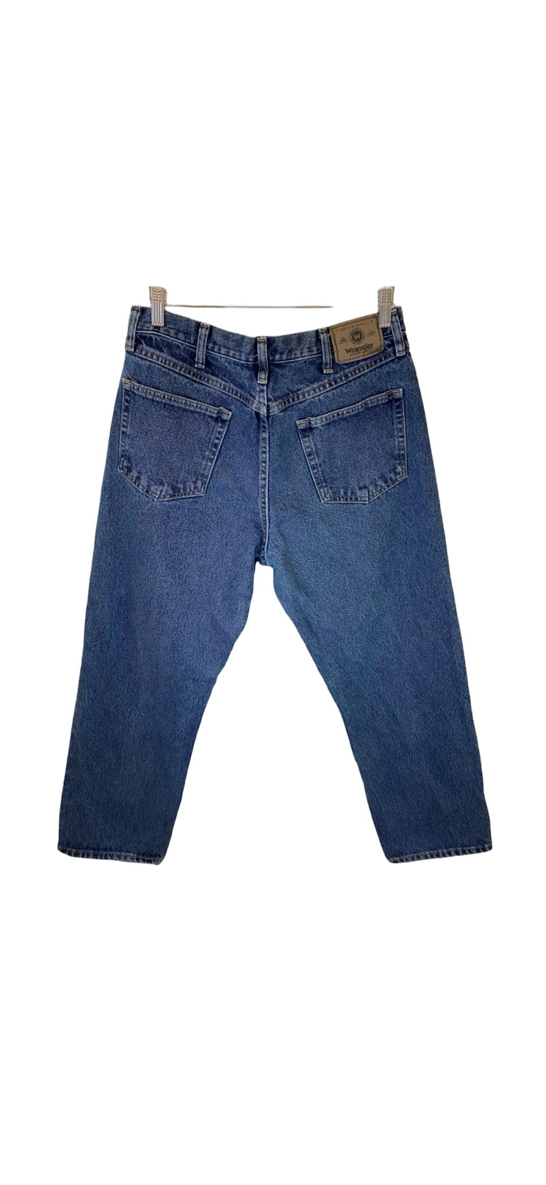 Pode incluir: Um par de cal&ccedil;as de ganga azul com uma etiqueta Wrangler de couro castanho no bolso de tr&aacute;s.