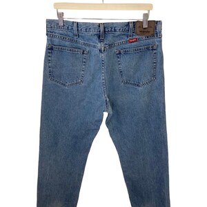 May include: A pair of light blue denim jeans with a brown leather patch on the back pocket that says "Wrangler".