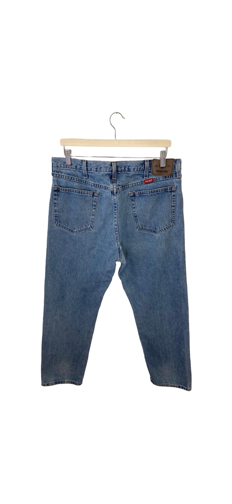 May include: A pair of light blue denim jeans with a brown leather patch on the back pocket that says "Wrangler".