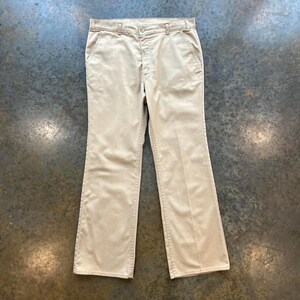 May include: A pair of beige straight-leg pants with a button fly and belt loops.