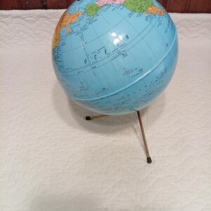 Peut inclure: Un globe vintage avec un océan bleu clair et des continents colorés. Le globe est monté sur un support en métal de couleur laiton. Le globe présente le texte "OCEAN" et "SANDWICH".