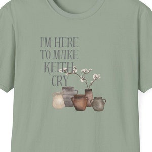 Puede incluir: Una camiseta verde claro con el texto "I'm here to make Keith cry" y una ilustración de acuarela de cinco jarrones de cerámica marrón con flores blancas.