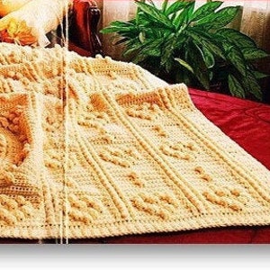 May include: A crochet pattern for a cream-colored blanket with a textured design. The blanket is laid out on a bed with a red coverlet. The text "Crochet Pattern" is displayed in red letters on a white background.