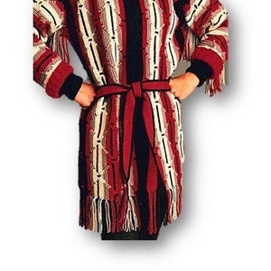 May include: A long, striped crocheted coat with a hood and a belt. The coat is made in a variety of colors, including red, white, and black. The coat has a fringe trim.