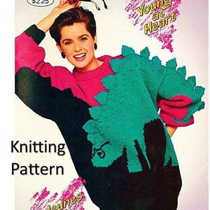 May include: Knitting pattern for a sweater with a dinosaur design. The sweater is black, pink and teal. The pattern is from Patons "Young at Heart" collection.