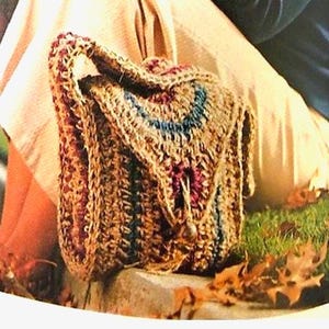 May include: A crocheted bag in shades of brown, with accents of blue and red. The bag has a flap closure and a handle. The text "Fast & Easy" and "70's Crochet Pattern" are displayed above and below the bag.