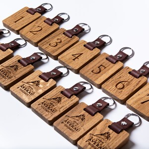 May include: Ten wooden keychains with leather straps. Each keychain has a number from 1 to 7 and the words "Hotel Averau" with a mountain graphic.