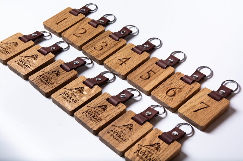May include: Ten wooden keychains with leather straps. Each keychain has a number from 1 to 7 and the words "Hotel Averau" with a mountain graphic.