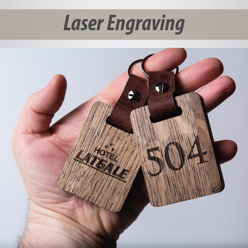 May include: Two wooden keychains with leather straps. One keychain is engraved with "HOTEL LAITGALE" and the other is engraved with "504".