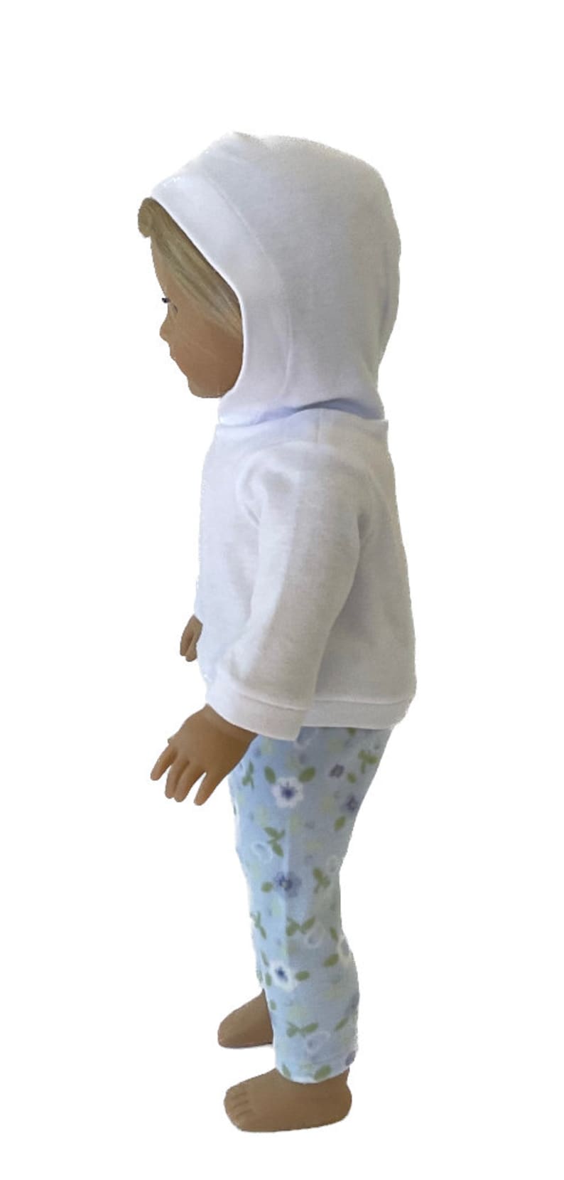 May include: A doll wearing a white hooded sweatshirt and light blue floral print pajama pants. The doll's outfit is designed for comfort and play, perfect for imaginative adventures. The doll is standing.