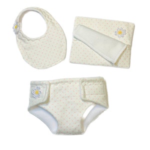 Puede incluir: Un juego de cuidado para bebés que incluye un babero, un pañal y un cambiador. Cada artículo es blanco con un estampado de lunares rosas y un borde festoneado. Un aplique de margarita adorna el babero y el pañal. El cambiador tiene un inserto absorbente blanco.