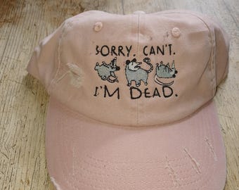 Könnte beinhalten: Rosa Baseballkappe mit einem gestickten Design aus drei Opossums und dem Text "Sorry. Can't. I'm Dead."