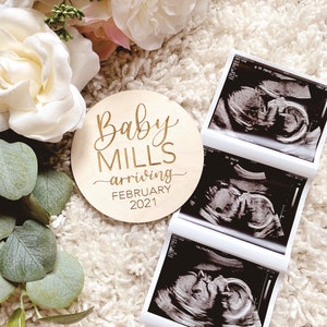 May include: A wooden sign with the text "Baby Mills arriving February 2021" and three black and white ultrasound images.