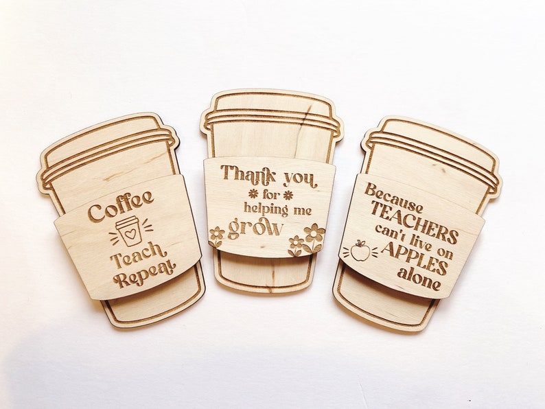 Puede incluir: Tres posavasos de madera para tazas de caf&eacute; con lemas grabados. El primer posavasos dice "Coffee Teach Repeat". El segundo posavasos dice "Thank you *for* helping me grow". El tercer posavasos dice "Because Teachers can't live on Apples alone".