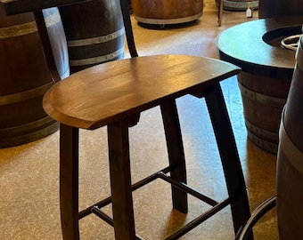 May include: A dark brown wooden bar stool with a curved seat and backrest. The stool has a sturdy frame with a footrest and is surrounded by other wooden furniture. The stool's height is approximately 30 inches.