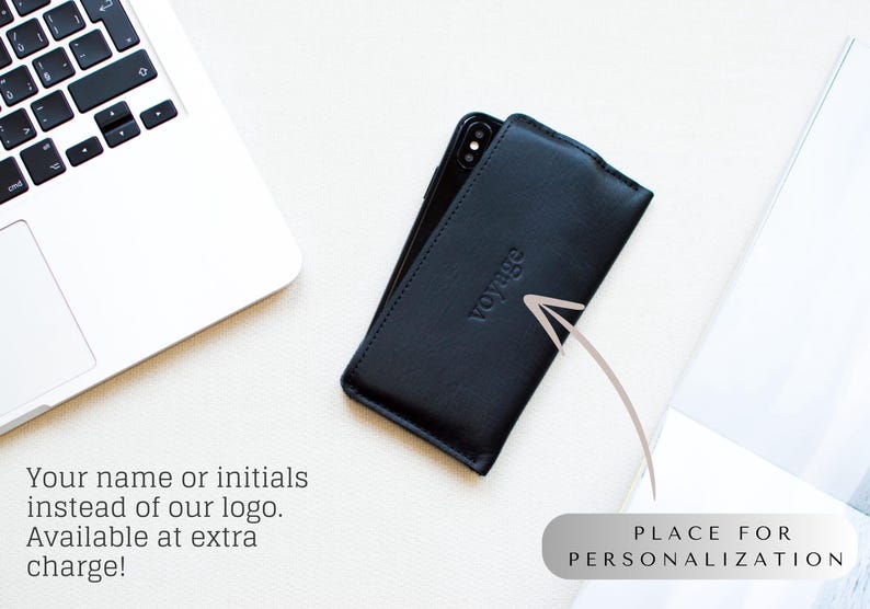 May include: Black leather phone case with the word "voyage" embossed on the front. The case is on a white surface next to a laptop. Text on the image says "Your name or initials instead of our logo. Available at extra charge!" and "PLACE FOR PERSONALIZATION."