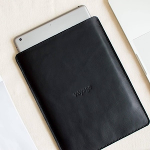 May include: Black leather tablet sleeve with the word "voyage" embossed on the front.