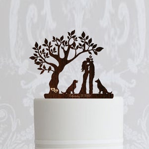 May include: A white three-tier wedding cake decorated with white roses and lavender. The top tier has a wooden cake topper featuring a couple kissing under a tree with two dogs.
