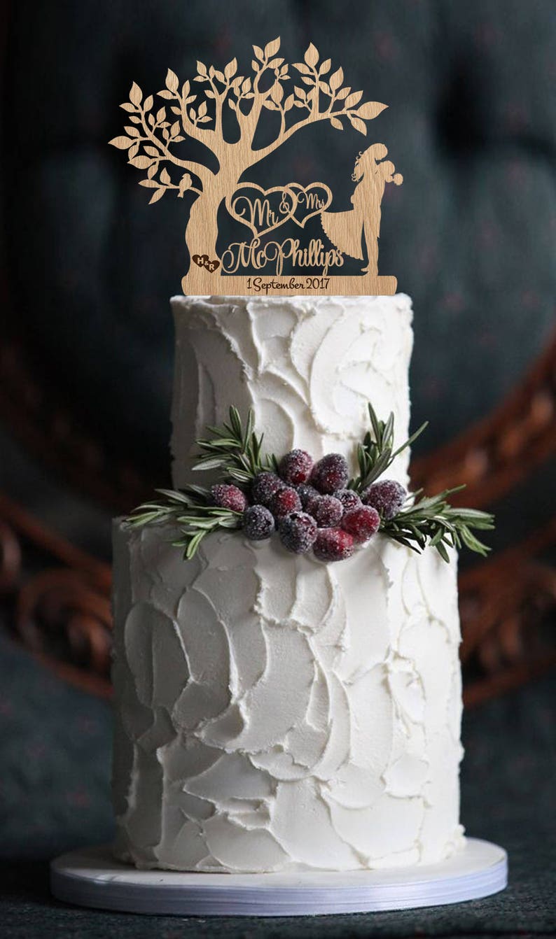 May include: A wooden wedding cake topper featuring a tree with two birds, a couple holding hands, and the text "Mr. & Mrs. Mc Phillips 1 September 2017".