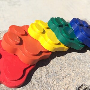 May include: A set of six paw print shaped silicone molds in rainbow colors: red, orange, yellow, green, blue, and purple.