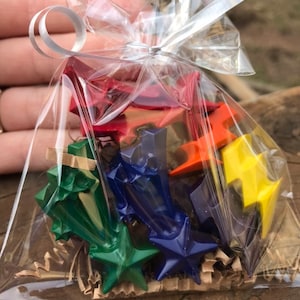 Könnte beinhalten: Eine durchsichtige Plastiktüte gefüllt mit bunten sternförmigen Buntstiften. Die Stifte sind in einem Regenbogenmuster angeordnet, mit roten, orangen, gelben, grünen, blauen und violetten Buntstiften.