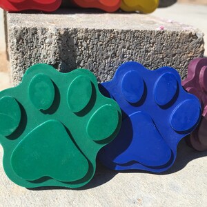 May include: Three colorful paw print shaped toys made of rubber. The paw prints are green, blue, and purple.