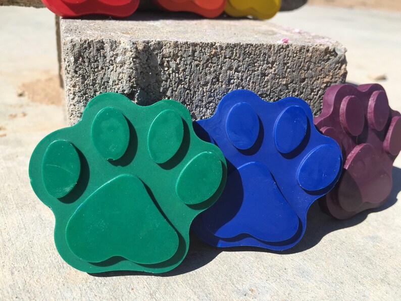 May include: Three colorful paw print shaped toys made of rubber. The paw prints are green, blue, and purple.