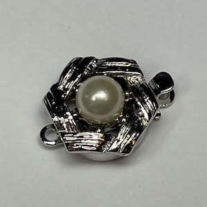 May include: Silver tone clasp with a woven design and a white pearl in the center.
