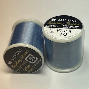 May include: A spool of light blue beading thread, labeled "MIYUKI Beading Thread 330dtex 100% NYLON Made in Japan LOT. HTO1R COL. 10 TEL. 084-972-4741", with a label on the bottom that reads "MIYUKI Beading Thread ビーズステッチ糸 50m (55yds.) フィルム、PET"
