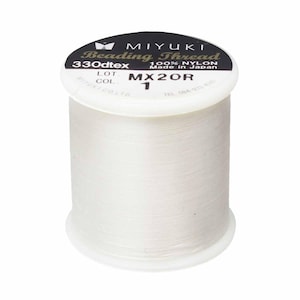 May include: A spool of white Miyuki beading thread made of 100% nylon. The label on the top reads Miyuki Beading Thread, 330dtex, 100% Nylon, Made in Japan, and color number 1. The thread is wound around a white plastic cylindrical spool.
