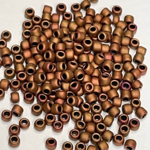 May include: A pile of small, round, copper-colored beads with a matte finish.