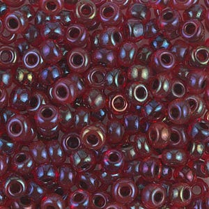 May include: A close-up of a pile of small, round beads. The beads are a deep red color with an iridescent sheen, reflecting hints of blue, green, and gold. Each bead has a central hole for stringing.