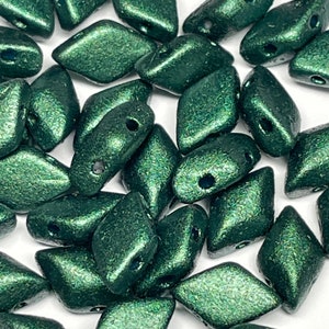 May include: A collection of dark green, faceted, glass beads with a metallic sheen. The beads are shaped like a diamond with rounded edges.