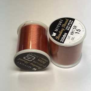 May include: Two spools of brown beading thread, each with a label that reads "MIYUKI Beading Thread 330dtex 100% NYLON Made in Japan LOT. HH15R COL. 15 MIYUKICO.LTD. TEL 084-972-4747".