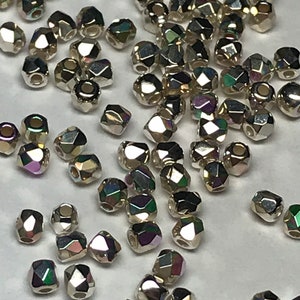 May include: A large quantity of iridescent silver faceted glass beads. The beads are small and have a hexagonal shape.