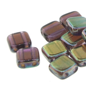 May include: A group of iridescent square glass beads with a brown and purple color scheme. The beads have a striped pattern and are designed for jewelry making.