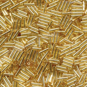 May include: A close-up image of a large quantity of gold-colored glass beads. The beads are small and cylindrical in shape.