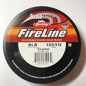 May include: A spool of FireLine microfused braided bead thread by The Beadsmith. The label is black, red, and orange, with the brand name and product details. The spool contains 8LB of Crystal thread, 125YD, and is 0.007in in diameter.