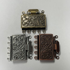 May include: Three ornate metal clasps for jewelry making. The clasps are rectangular with a floral design and have five loops on each side. The clasps are in silver, gold, and copper.