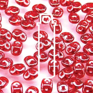 May include: Close-up of a collection of red glass beads. The beads are oval-shaped with a glossy finish and a white design. The beads are scattered across a light background.