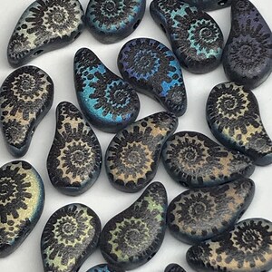 May include: A collection of black and blue glass beads with a swirling pattern. The beads are shaped like teardrops and have a glossy finish.