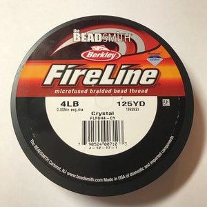 May include: A spool of Berkley FireLine Crystal microfused braided bead thread in red, white, and black. The spool is labeled with the text "4LB 125YD 0.005in avg.dia FLFSH4-CY 1392823".