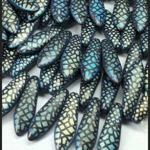 K&ouml;nnte beinhalten: Nahaufnahme einer Ansammlung von blauen und wei&szlig;en Glasperlen mit geometrischem Muster. Die Perlen sind oval geformt und haben eine gl&auml;nzende Oberfl&auml;che.