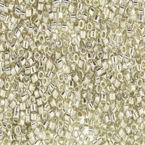 May include: A close-up image of a large quantity of silver seed beads. The beads are small and round, with a metallic sheen.