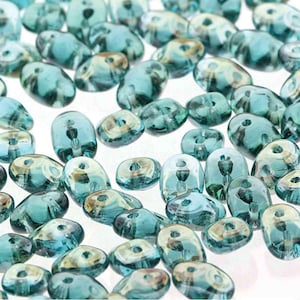 May include: A collection of teal blue glass beads with a slightly iridescent finish. The beads are oval shaped with a hole in the center.
