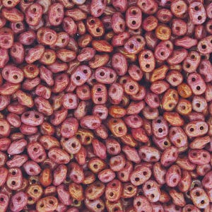May include: A close-up of a pile of small, red and orange glass beads. The beads are shaped like teardrops with two holes in each bead.