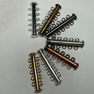 May include: Assortment of six metal connector clasps for jewelry making. The clasps are in various finishes, including silver, gold, copper, and black.