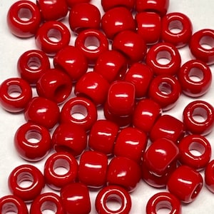 May include: A large pile of red plastic beads. The beads are round and have a hole in the center. They are perfect for making jewelry or other crafts.